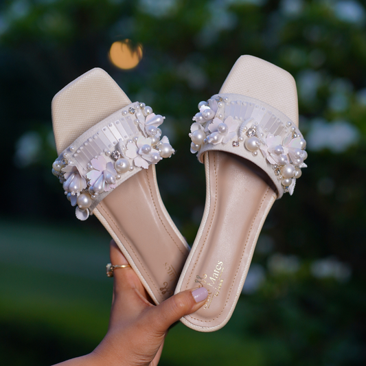 Bombshell Handcrafted Heel Sliders by Solemates by Palak — ivory pearl and 3D floral embellished block heel sliders held against garden background