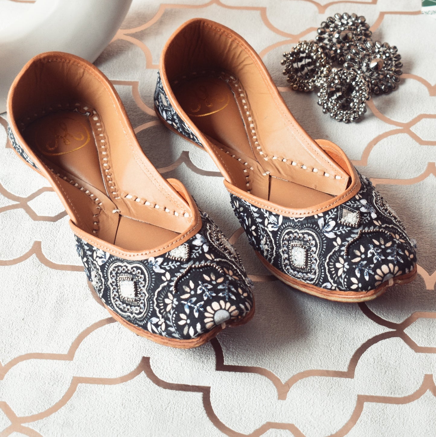 Monochrome Magic Jutti by Solemates by Palak — navy-grey 
floral printed jutti with silver bead embellishment, flat lay with silver earrings