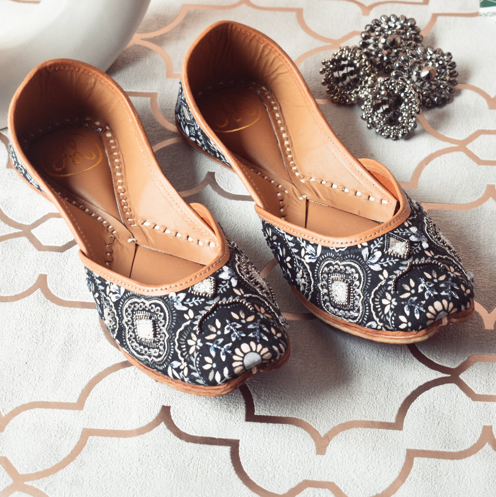 Monochrome Magic Jutti by Solemates by Palak — navy-grey 
floral printed jutti with silver bead embellishment, flat lay with silver earrings